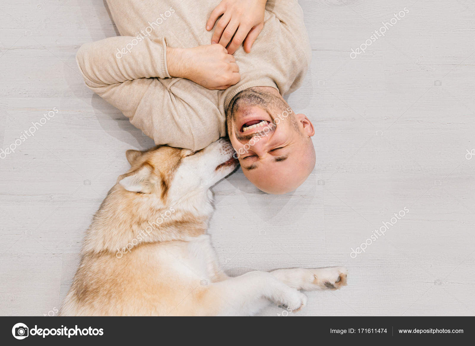 Glücklich lachender erwachsener Mann auf Holzboden liegend. Männer mit