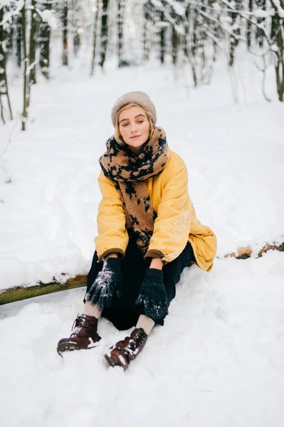 Странная странная женщина лежит на дереве в снежном зимнем лесу. Молодая симпатичная девушка, отдыхающая на свежем воздухе. Необычная женщина отдыхает на природе. Одинокая женщина путешествует в морозный день. — стоковое фото