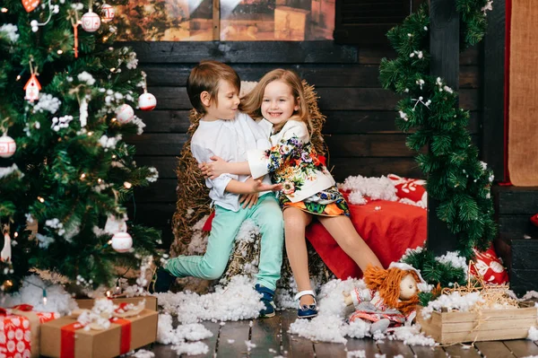 Rapaz e rapariga apaixonados. Árvore de Natal e decorações de ano novo. Miúdos adoráveis a abraçarem-se. Férias de inverno. Jovens do sexo masculino e feminino brincando e rindo em estúdio. Crianças emoções alegres . — Fotografia de Stock