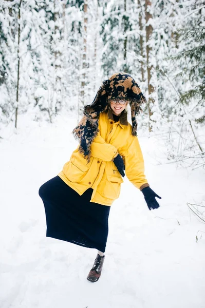 Oneven vreemde jonge bizarre fancy eenzaam meisje in rare houdingen in winter besneeuwde forest maken op weekend. Modieuze gekke kinky vrouw in glazen en warme trendy kleding buiten ontspannen. Gek hoofdtooi. — Stockfoto