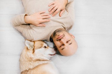 İri köpekli yetişkin kel bir adam yerde uyuyor. Evde evcil hayvanla birlikte. Nazik ve duygusal duygular. Güzel köpek, genç bir erkekle dinleniyor. Evcil hayvanlı bir adam birbirine sarılıyor..