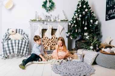 Çocuklar yeni yıl iç odasında oynarken. Crhistmas ağaç topları ile. Kış tatil ruh hali. Mutlu çocuklar oyuncak zevk. Oturma ve şaka genç arkadaşlar. Erkek ve kız birlikte. Bayramı kutluyor.