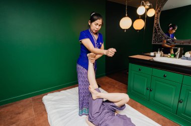 Oryantal egzotik elbiseli yapma ve Avrupalı güzel Bayan pijama yeşil gevşeme yoga Studio için farklı geleneksel spa töreni yordamlar gösteren genç Tay masör eğitmen kız.