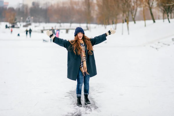 冬の暖かい服を着た若い陽気で幸せな奇妙なクレイジーな女の子は、凍った湖の屋外で楽しみを得る。氷の上を走るかわいい面白い女性の人。自然雪の12月の週末。霜の日. — ストック写真