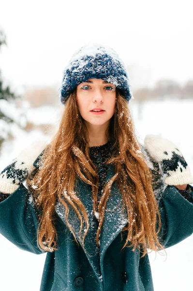 Snow queen. Young girl with amazing beautiful face, blue fantsastic eyes and long perfect hair closeup portrait outdoor. Freezing skin. Eyelashes and lips covered with snow. Fairy fantasy unusual lady