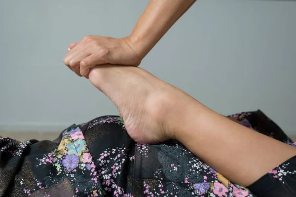 Массаж: терапевт массирует ноги и ноги азиатской женщины — стоковое фото