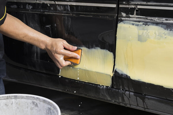 Auto body repair series: Closeup of mechanic sanding putty filler