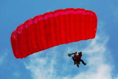 İki kişi tandem atlama ile mavi gökyüzünde kırmızı paraşüt