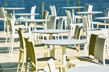 Beyaz masa ve sandalyeler denizin kenarında boş açık hava kafe