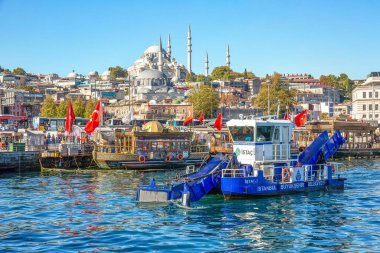 ISTANBUL, TURKEY -  October 9th, 2019: View to Eminonu pier and Suleymaniye mosque across Bay of Golden Horn. Special ship cleans the water in the morning