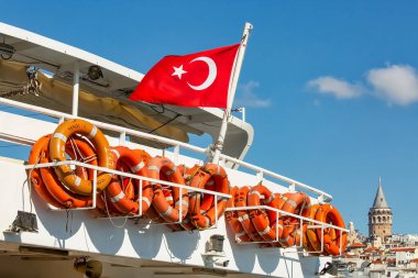 ISTANBUL, TURKEY - October 9th, 2019: Turkish flag and lifebuoys on the board of a ship, Galata Tower in the background