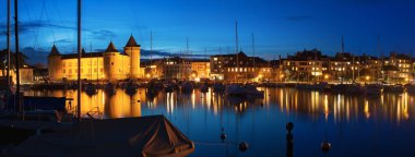 MORGES, SWITZERLAND - March 5th, 2018: Beautiful night time panorama with Morges Castle and boats in the harbour