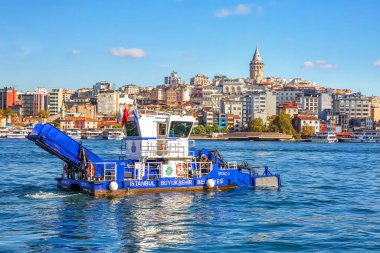 ISTANBUL, TURKEY -  October 9th, 2019: View to Galata Tower across Bay of Golden Horn. Special ship cleans the water in the morning