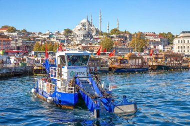 ISTANBUL, TURKEY -  October 9th, 2019: View to Eminonu pier and Suleymaniye mosque across Bay of Golden Horn. Special ship cleans the water in the morning