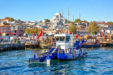 ISTANBUL, TURKEY -  October 9th, 2019: View to Eminonu pier and Suleymaniye mosque across Bay of Golden Horn. Special ship cleans the water in the morning