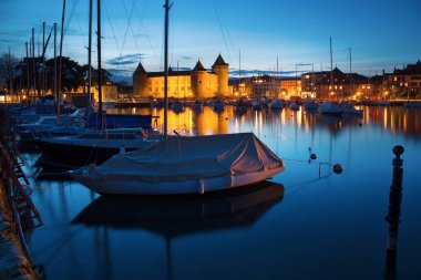 MORGES, SWITZERLAND - March 5th, 2018: Beautiful night time panorama with Morges Castle and boats in the harbour