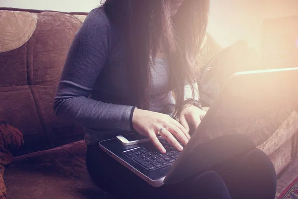 Girl sitting on the couch and working with laptop — Stock Photo, Image