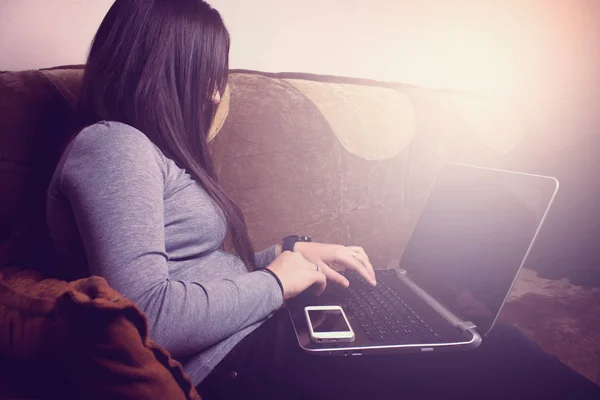Ragazza seduta sul divano e lavorare con il computer portatile — Foto Stock