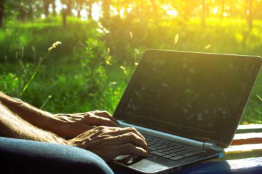 Adam dışarıda bilgisayarla çalışıyor.