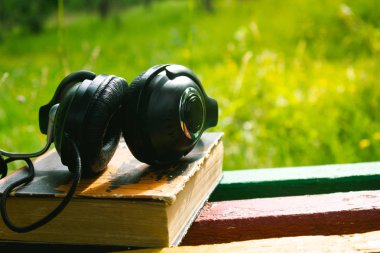 Ahşap bir masanın üzerinde kitap olan kulaklıklar.