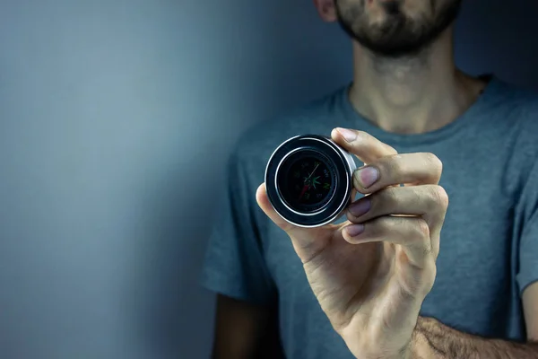 Un jeune homme tient une boussole dans sa main et montre — Photo