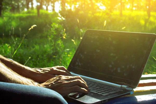 Adam dışarıda bilgisayarla çalışıyor.