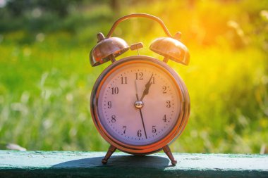 Saat yeşil bahçede, ahşap masada. 