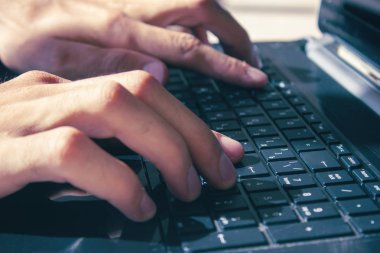 Genç adam bilgisayarla çalışıyor.