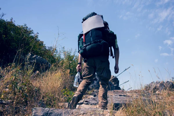 Hiker in a backpack rises in the mountains — Stock Photo, Image