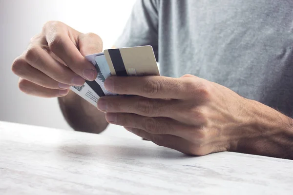 a young man holds up a few credit cards