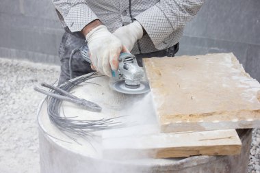 Kesici makineyle taş bloğu kesen işçiler.