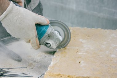 Kesici makineyle taş bloğu kesen işçiler.