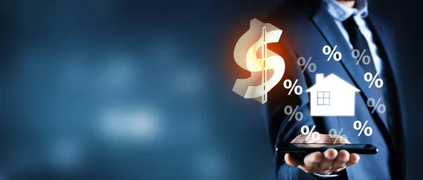Бизнесмен держит в руках доллар и дом с процентами — стоковое фото