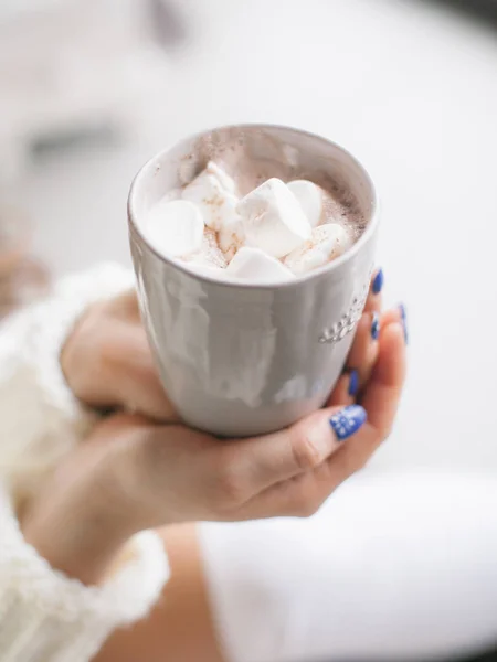 Cup of cacao with marshmallow in hands