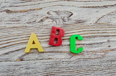 Ahşap arka plan üzerinde renkli plastik harf ABC yazım