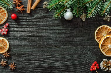 Noel ağacı dalları ve çam kozalakları ahşap, siyah arka planda.