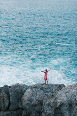 Genç adam okyanusun Uçurumdaki dururken kucaklayan