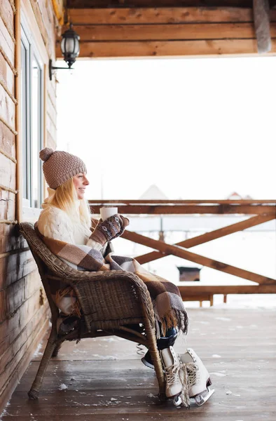 Mujer joven en forma de punto está bebiendo té mientras está sentado en la silla después de patinar sobre hielo — Foto de Stock