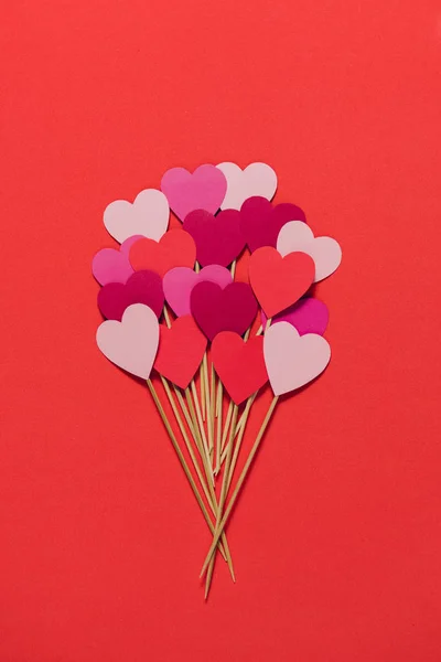 Καρδιές χαρτί σε ξύλινα sticks σε κόκκινο φόντο — Φωτογραφία Αρχείου