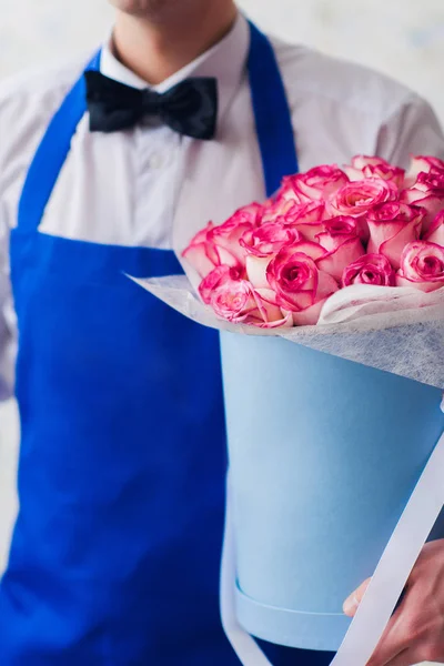 Junger Mann Kurier hält Blumenstrauß in Schachtel — Stockfoto