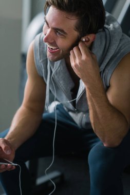 En iyi şarkı onun eğitimi için. Genç yakışıklı adam akıllı telefonunu kullanarak ve müzik kulaklık