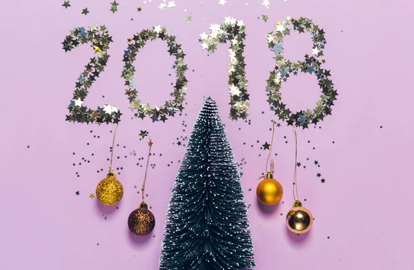 New Year 2018 writing composed of glittering confetti in the shape of stars over Christmas tree. New Year 2018 writing composed of glittering confetti over Christmas tree.