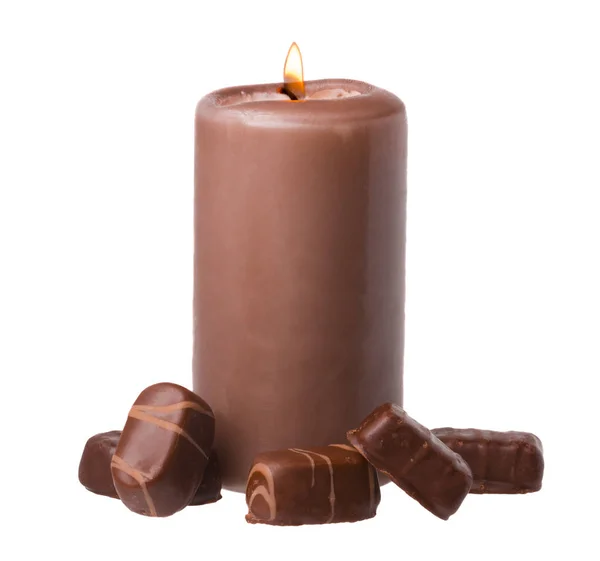 Свеча с шоколадными конфетами на белом фоне Стоковое Фото