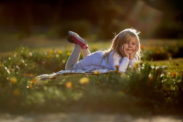 Slunečný den, malá holčička leží na trávě — Stock fotografie
