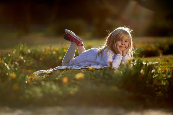 Sunny day, the little girl lies on the grass — Stock Photo, Image