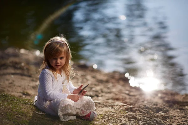 Petite fille jouer sur la rive de la rivière — Photo