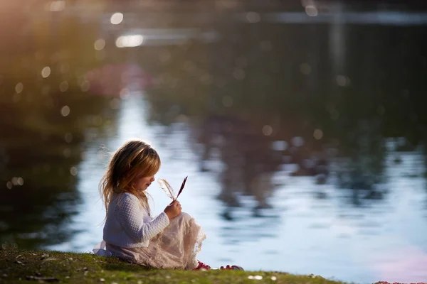 小さな女の子が川の土手で遊んで — ストック写真