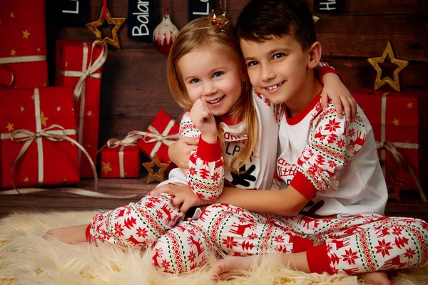 Crianças de pijama no fundo de presentes — Fotografia de Stock