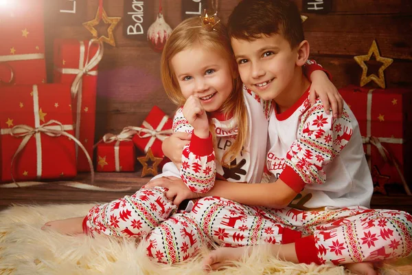 Crianças de pijama no fundo de presentes — Fotografia de Stock