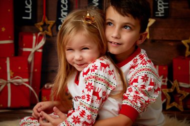 ve sevimli erkek kardeşim yatakta Noel ağacı arka plan üzerinde oynarken pijama. Yılbaşı gecesini